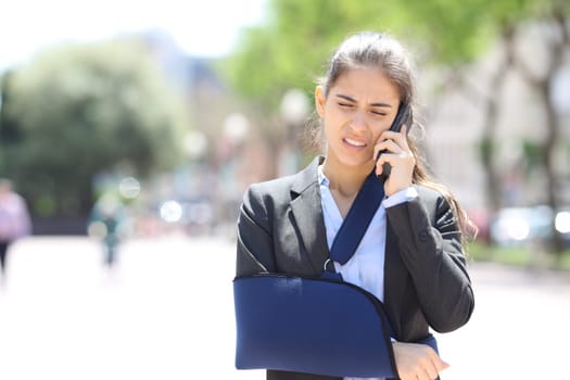 Front view of a convalescent executive talking on phone and complaining in the street
