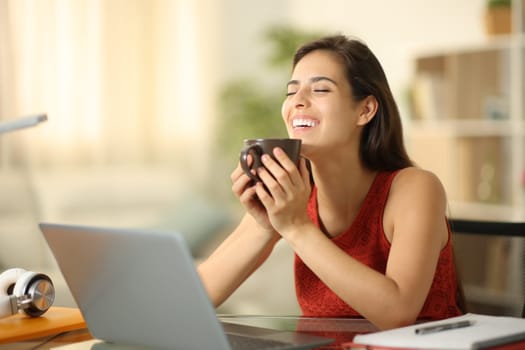 Happy student laughing drinking coffee and breathing relaxing at home