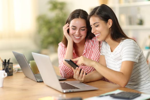 Happy tele workers wasting time checking phone at home