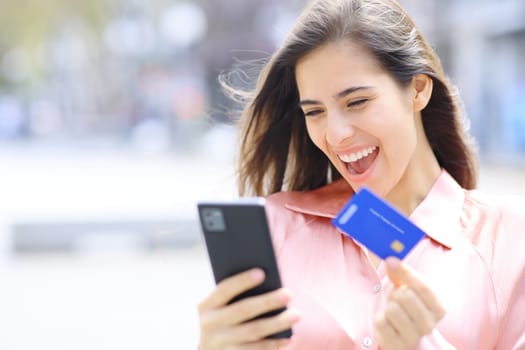 Excited elegant woman buying online with phone and credit card