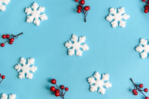 Minimal christmas, new year and winter holiday composition. Flat lay. Creative pattern banner with snow flakes nad red berries on pastel blue background. Christmas and wintertime concept. Top view.