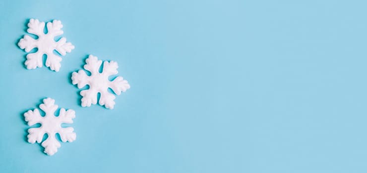 Minimal christmas, new year and winter holiday composition. Flat lay. Creative banner with snow flakes on pastel blue background. Christmas and wintertime concept. Top view.