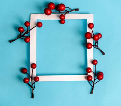 Christmas and new year background composition. Empty photo frame with christmas decoration on pastel blue paper. Minimal winter holiday concept. Flat lay.