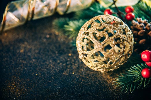 Christmas luxury still life with golden christmas ornament, fir tree and gold ribbon on dark vintage table. Closeup of luxury home decor for new year eve. Winter holiday greeting card background.