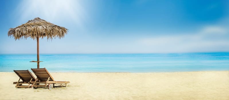 Summer holiday travel background. Tropical island luxury resort hotel vacation. Sun umbrella and chairs on sandy beach.