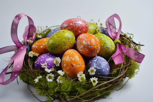 Colorful Easter eggs arranged in a decorative nest with ribbon accents