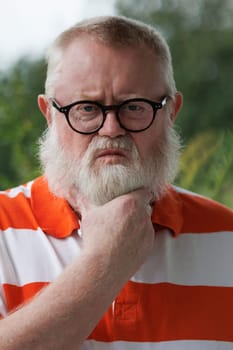 Angry senior man strokes his long beard.