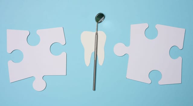Dentist's medical mirror and white paper puzzles on a blue background