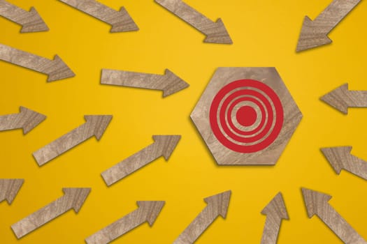 Wooden target and wooden arrows on a yellow background, target search concept