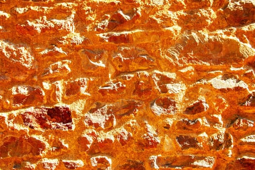 Brown yellow texture of a concrete wall. Closeup of brown  background of a concrete wall with a hilly uneven surface on a sunny day. Abstract backdrop.