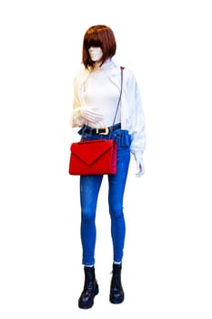 Female full length mannequin wearing a blue jeans trousers, a red handbag, a white jacket on blouse and black boots isolated on white. Woman wears trendy denim fashion.