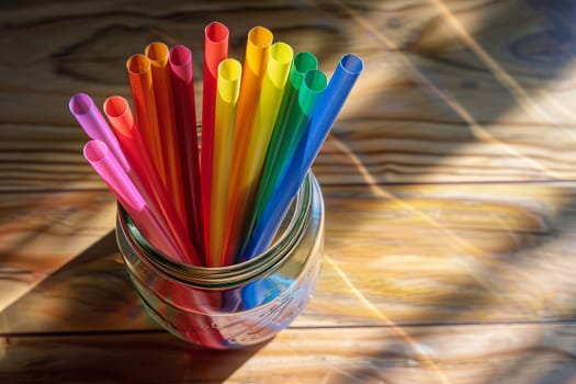 Rainbow-colored paper straws transparently arranged in a glass jar