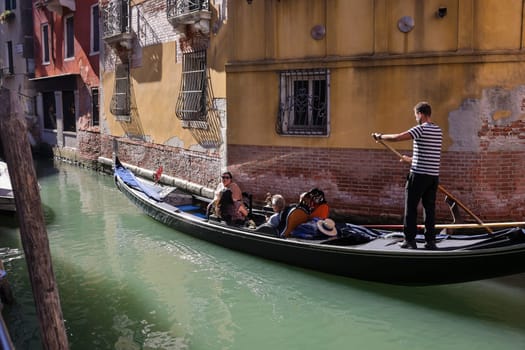 Venice, Italy - September 5, 2022: One of the most recognizable tourist attractions in the world - a gondola cruise through the narrow canals in Venice