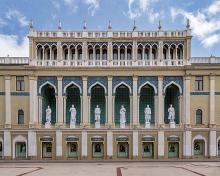 Nizami Museum of Azerbaijan, with statues lining the facade. The building is decorated with arches and intricate tile work, Baku, Azerbaijan