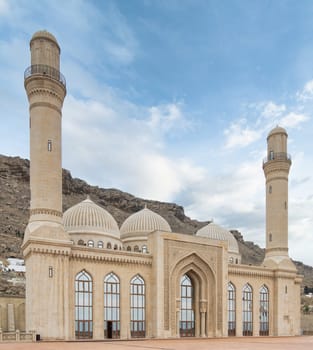 The Bibi-Heybat Mosque in Baku, Azerbaijan showcases stunning Islamic architecture with minarets, domes, and intricate details. Set against hills, it stands out against the clear blue sky