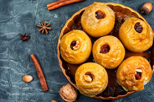 Baked apples with nuts and raisins in plate. Autumn seasonal dessert, roasted apples.