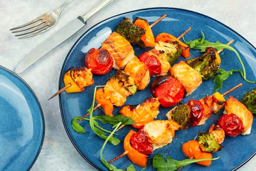 Grilled salmon fish kebab skewers with vegetables.