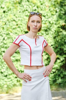 Redhead woman in tennis outfit looking at camera, three-quarter length daytime portrait