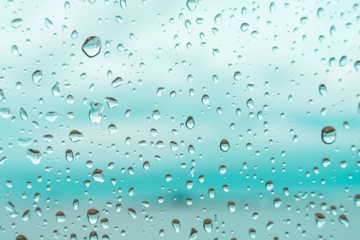 Drops on a window glass with blurry blue background close up , rain macro