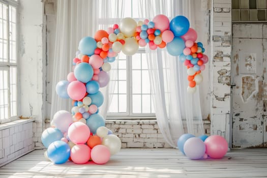 A room with a large arch made of balloons. The arch is blue, pink, and yellow