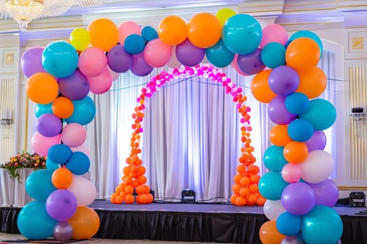 Colorful balloon arch framing a stage at a charity event, creating a festive backdrop