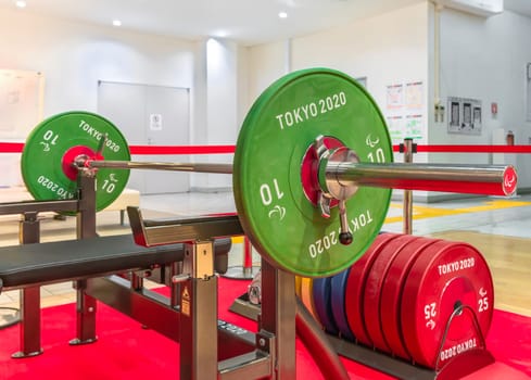 tokyo, japan - november 29 2021: A weightlifting barbell setup used at Tokyo 2020 Olympic and Paralympic Games featuring weight plates with 'Tokyo 2020' branding exhibited at Tokyo Sports Square.