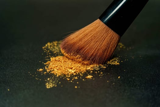A delicate makeup brush, its bristles generously dusted with shimmering gold powder.