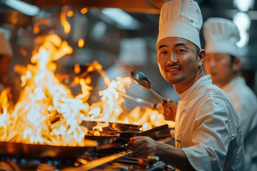 A professional chef is pictured in a busy kitchen with flames engulfing the pan as he cooks with concentration and skill