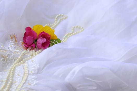Delicate close-up of a wedding dress with roses, poppy and pearls