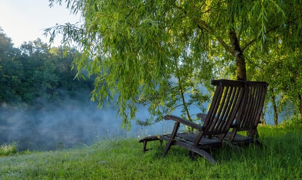a deck chair at the edge of the pond at sunrise