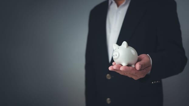 Money saving concept, Businessman holding the white piggy bank for saving money concept, Save for investment, banking, loan, home loan, Financial planning, education and healthy insurance.