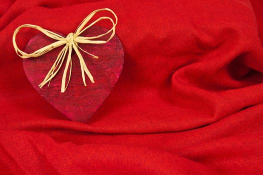Wooden red heart on red cloth as a symbol of love