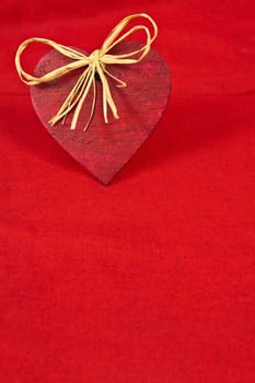 Wooden red heart on red cloth as a symbol of love