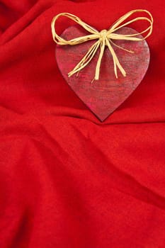 Wooden red heart on red cloth as a symbol of love