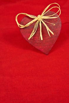 Wooden red heart on red cloth as a symbol of love