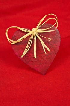 Wooden red heart on red cloth as a symbol of love