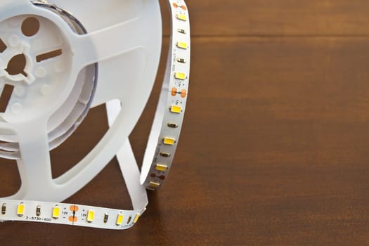 LED strip wound on a roll of brown wooden board