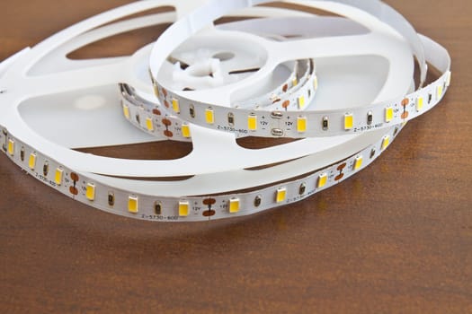 LED strip wound on a roll of brown wooden board