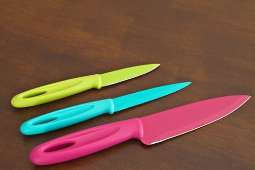 Set of large and small serrated kitchen knives color on a wooden board
