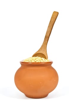 Manna croup in a clay pot with a wooden spoon on a white background