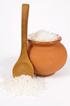 Sea salt crystals in clay pot with a wooden spoon