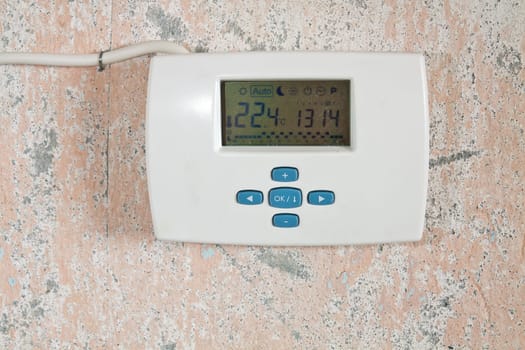 Electronic weekly programmer mounted on a wall with peeling paint