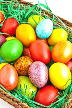 Colorful dyed Easter eggs placed in a wooden basket