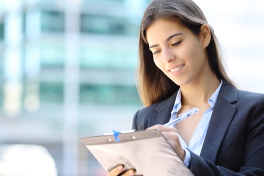 Satisfied businesswoman filling form standing in the street