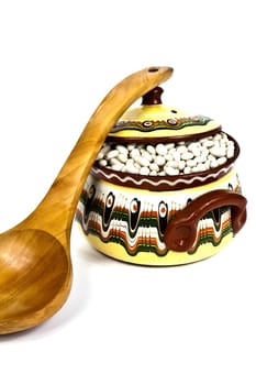 Supported on wooden spoon colored ceramic pot on a white background