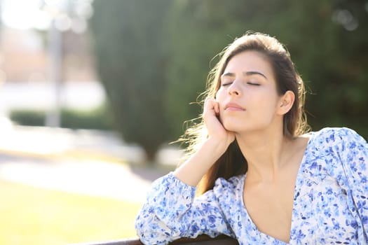 Woman relaxing sitting on a bench in a park alone