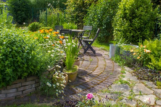 herb spiral in the garden with fresh herbs and flowers