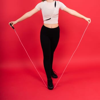 Cute teenage girl with a jumping rope looking at camera and smiling while having workout