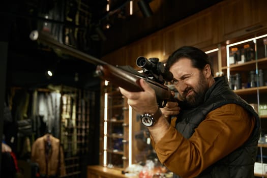 Man hunter customer aiming gun with telescopic sight while choosing ammunition in weapon store. Armament assortment for hunt hobby