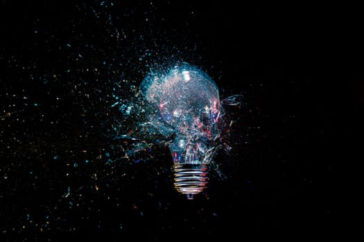 High-speed lightbulb exploding  glass shattering black background